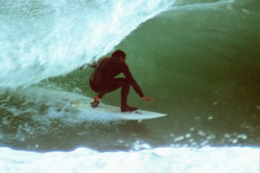 Picture of a man surfing a wave wearing a wetsuit