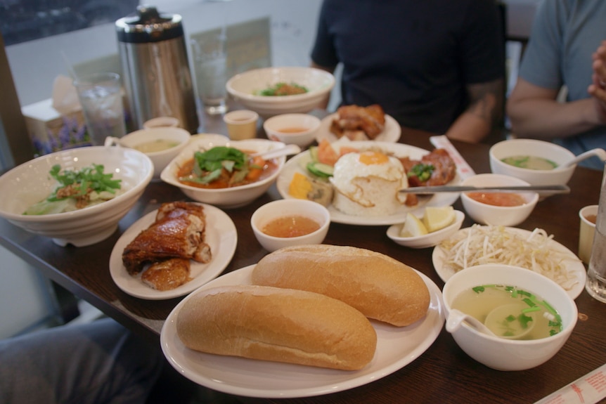 Vietnamese food including bagettes, rice, chicken, egg and soup. 