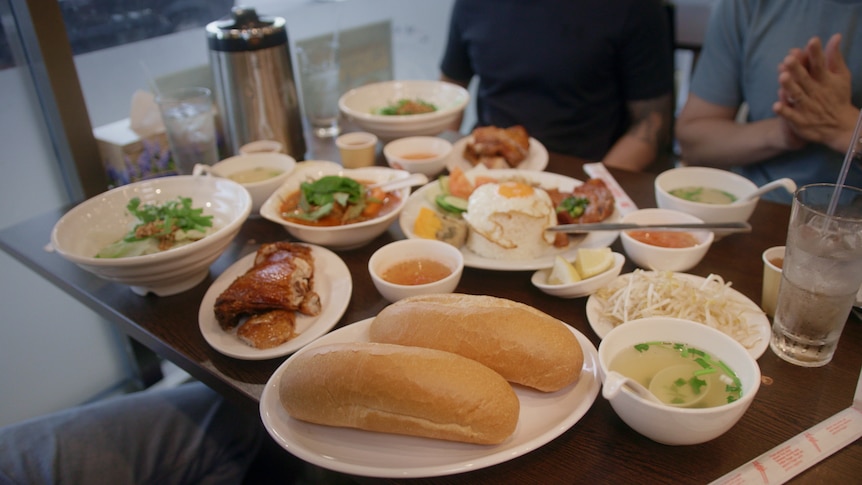 Vietnamese food including bagettes, rice, chicken, egg and soup. 