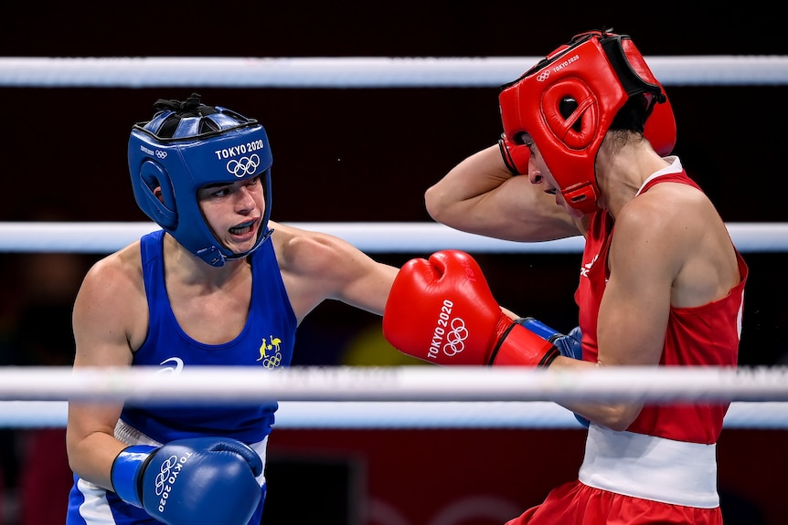 A women wearing blue boxing gloves punching another woman wearing red boxing gloves