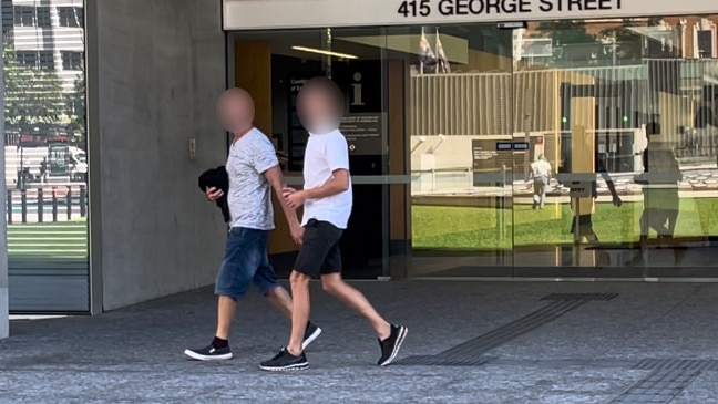 A blurred photo of a boy and his father leaving a Brisbane court.