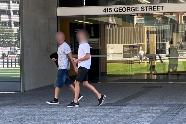 A blurred photo of a boy and his father leaving a Brisbane court.