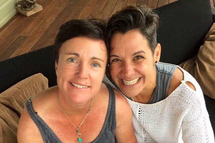 Two women with short brown hair hugging and smiling at the camera.