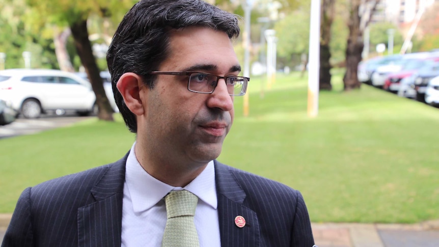 A head and shoulders shot of Nick Goiran wearing a suit and tie and glasses outside.
