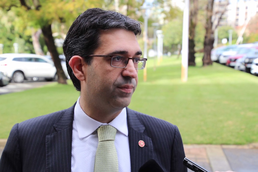 A head and shoulders shot of Nick Goiran wearing a suit and tie and glasses outside.