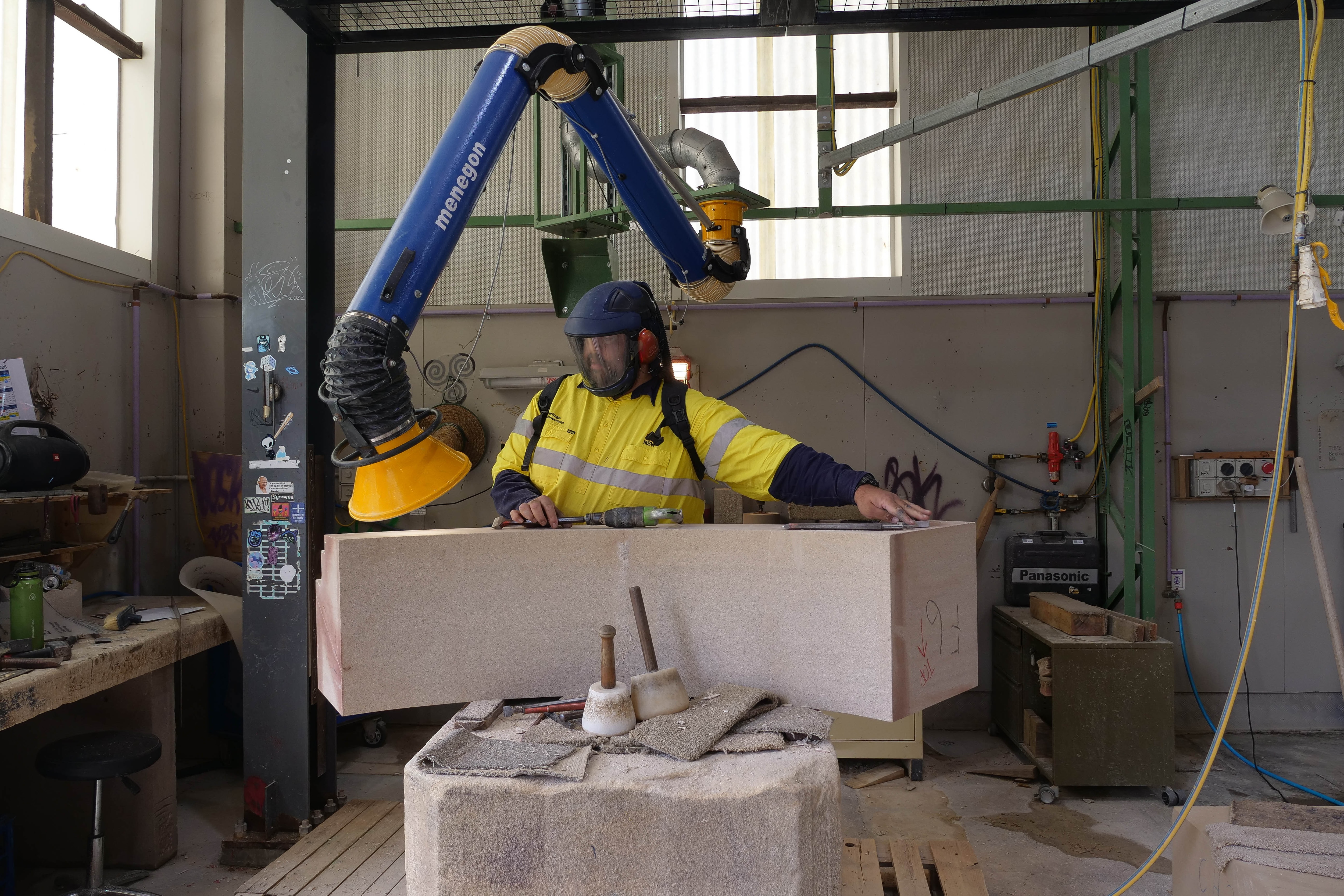 a man at a work station examines a large sandstone block