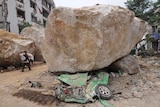A flattened taxi lies under a boulder in China