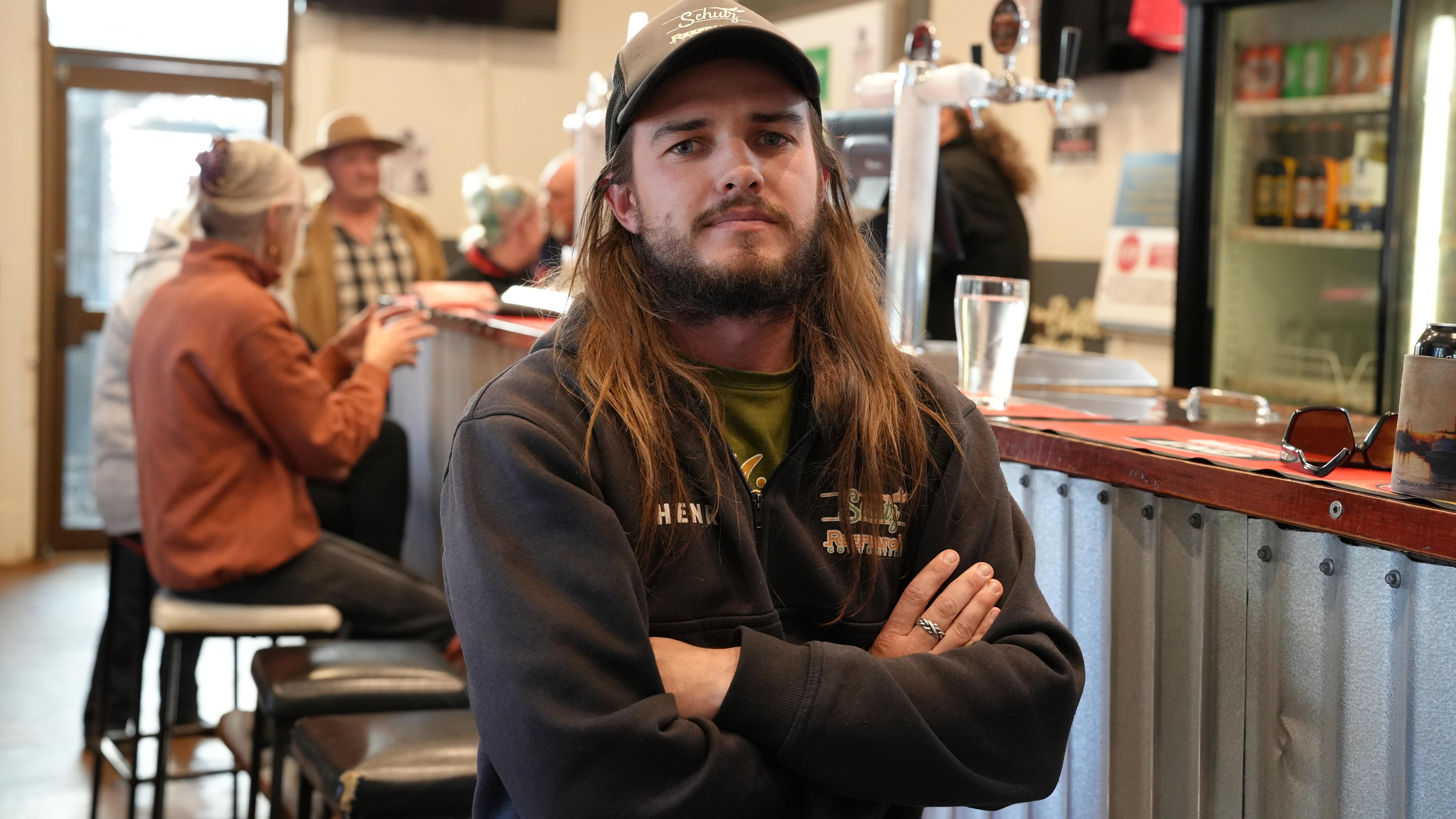 A man stands with crossed arms at a pub