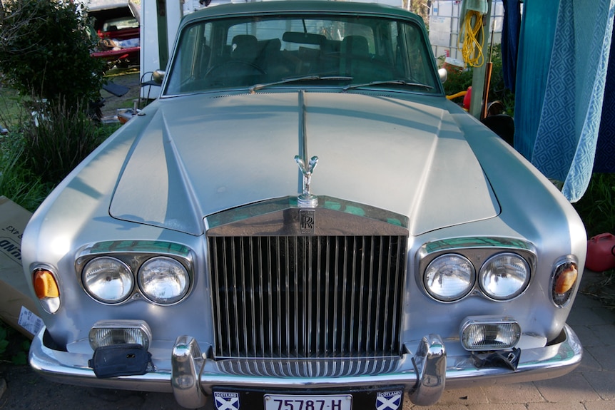 Silver vintage rolls royce car in a carport