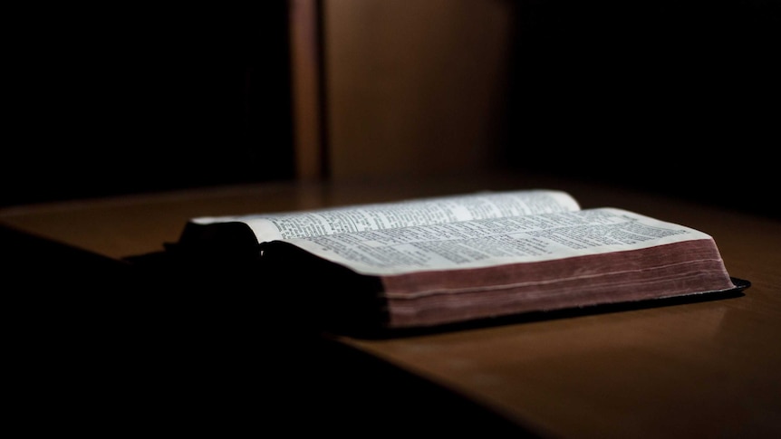 A bible lies open on a wooden desk