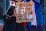 A woman holds up a sign saying 'Reject military coup. Justice for Myanmar'.