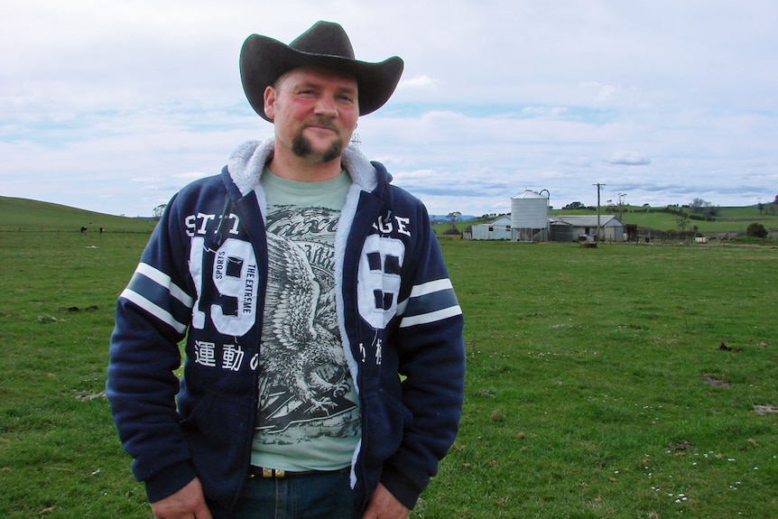 Regan Tucker standing in ryegrass and clover with his dairy in the background