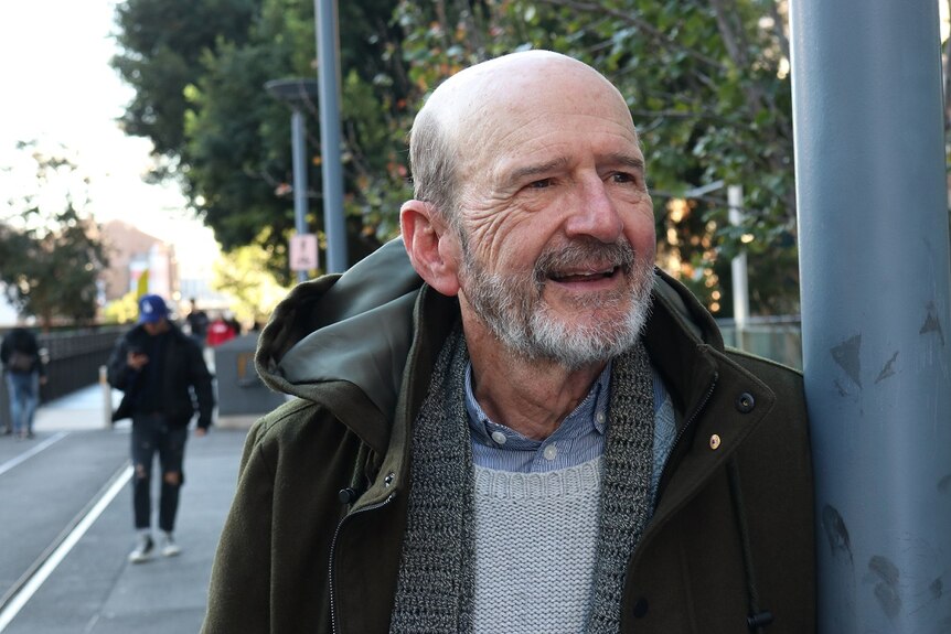 Garry McDonald stands in a Sydney street smiling.