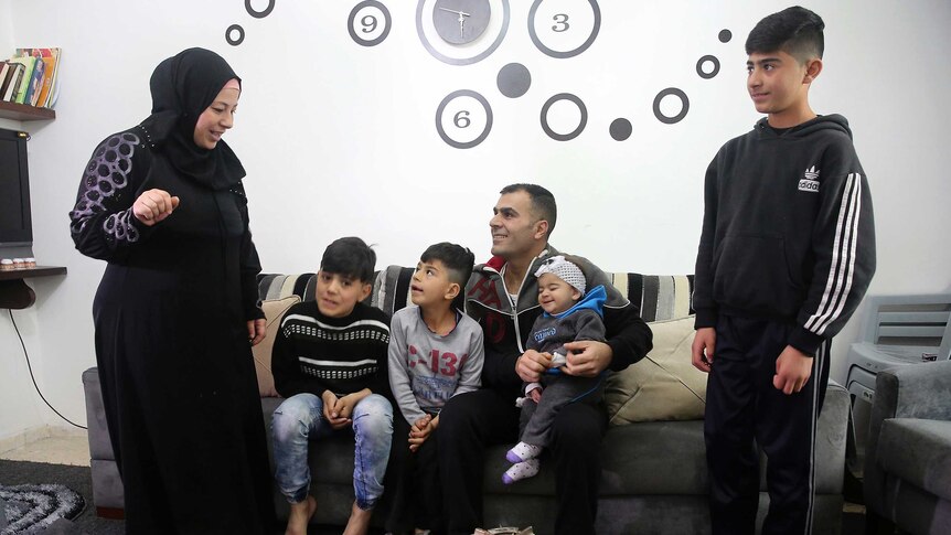 Ammar and Sanaa Sawan talk with their four children in their home in Jordan.