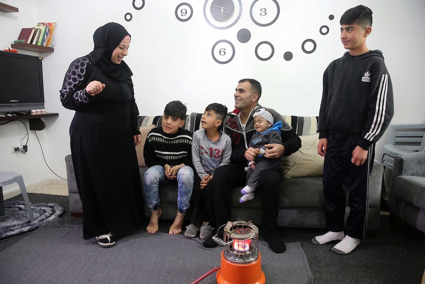 Ammar and Sanaa Sawan talk with their four children in their home in Jordan.