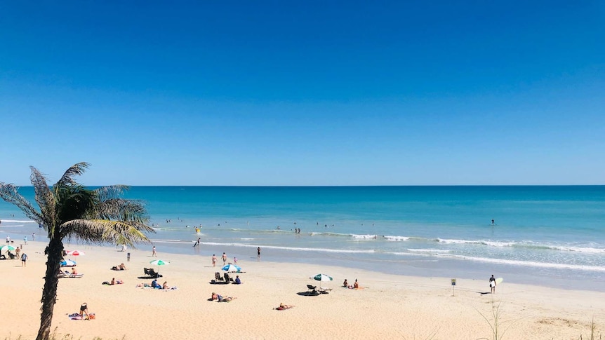 Blue water and white sand with people under umbrellas