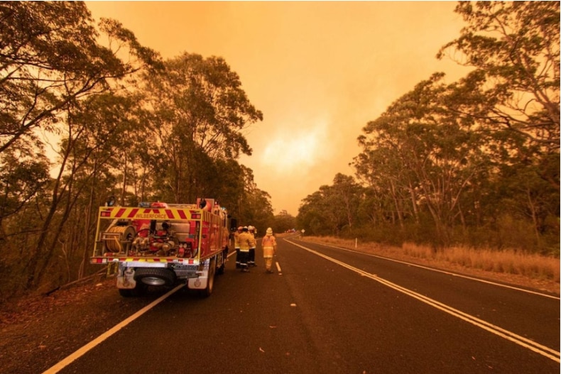 Firefighters under an orange sky.