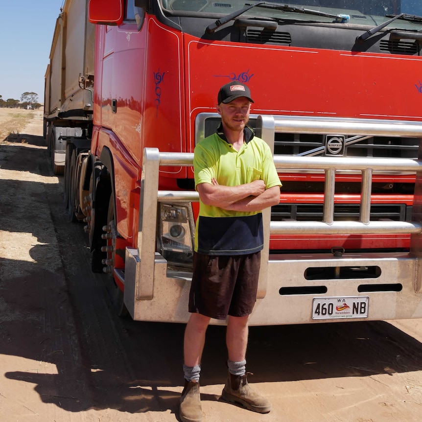 Man in high vis shirt stands beside big red truck