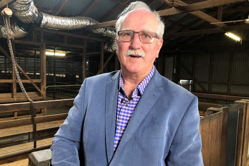 Mohair producer Doug Nicholls wearing a jacket standing inside a shearing shed.