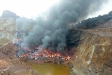 Thousands of tyres on fire and lots of smoke in a gully at a mine site.