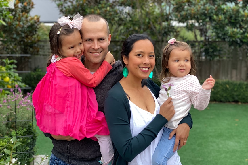 A man and a woman hold two little girls.