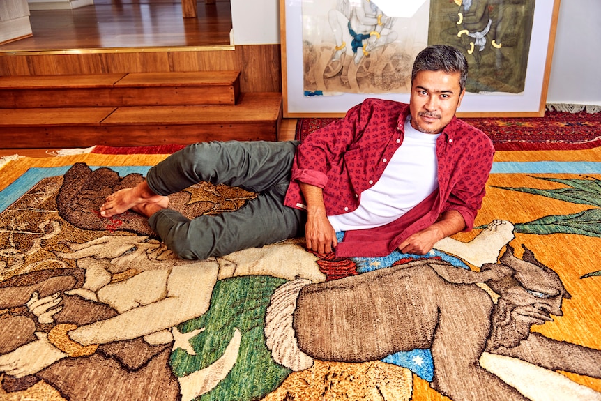 Artist Khadim Ali lying on a rug in his home