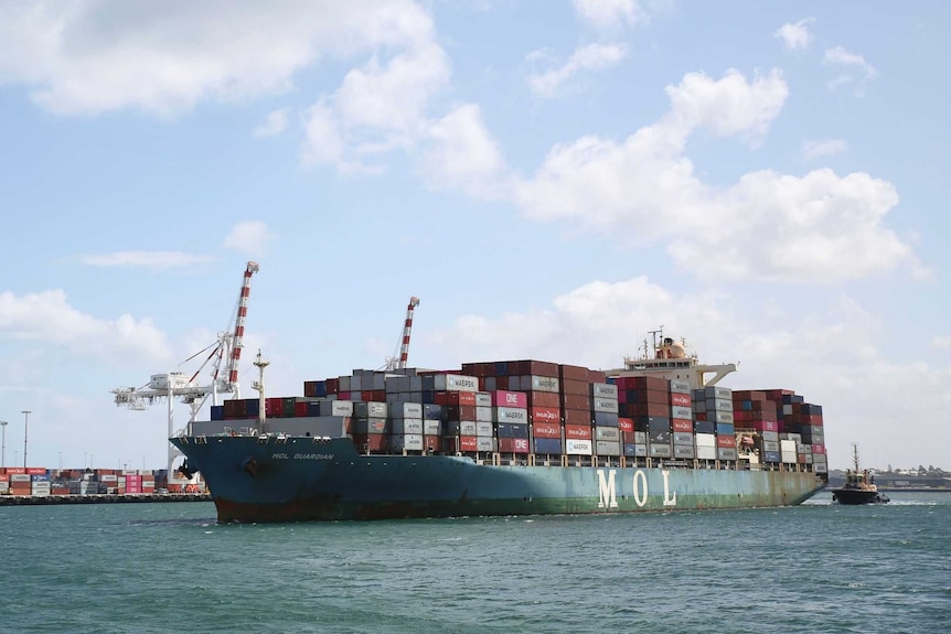 A container ship loaded up with different coloured containers pulls into Fremantle Port.