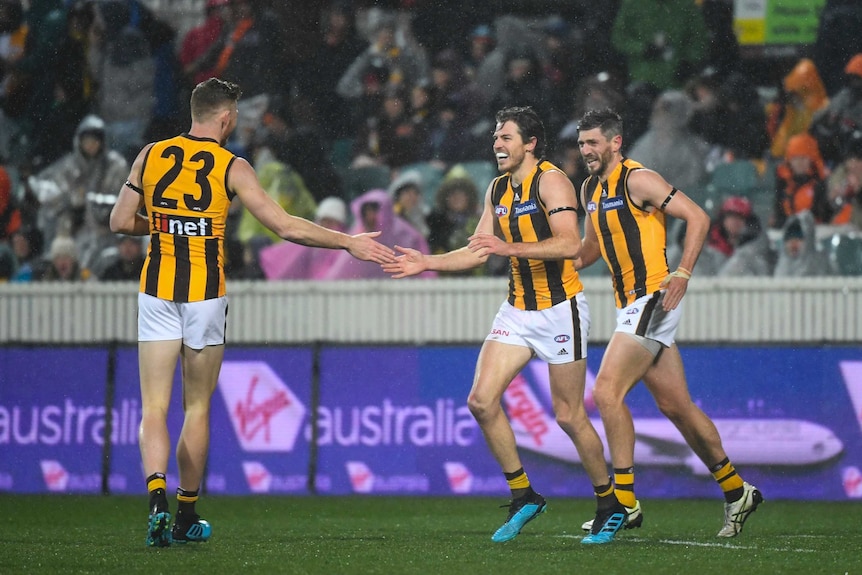 Isaac Smith grimaces while high-fiving a teammate. Snow can be seen falling.