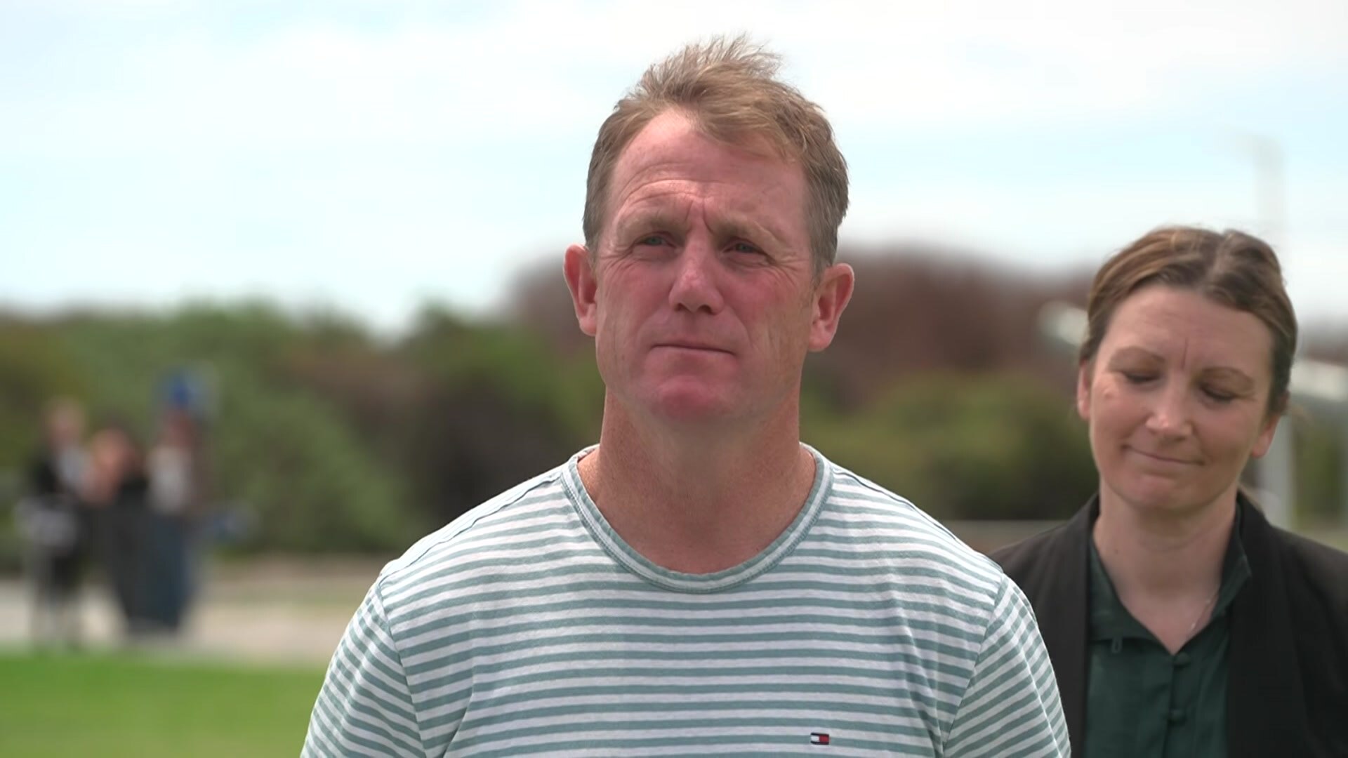 Um homem com cabelo loiro curto está em um parque.