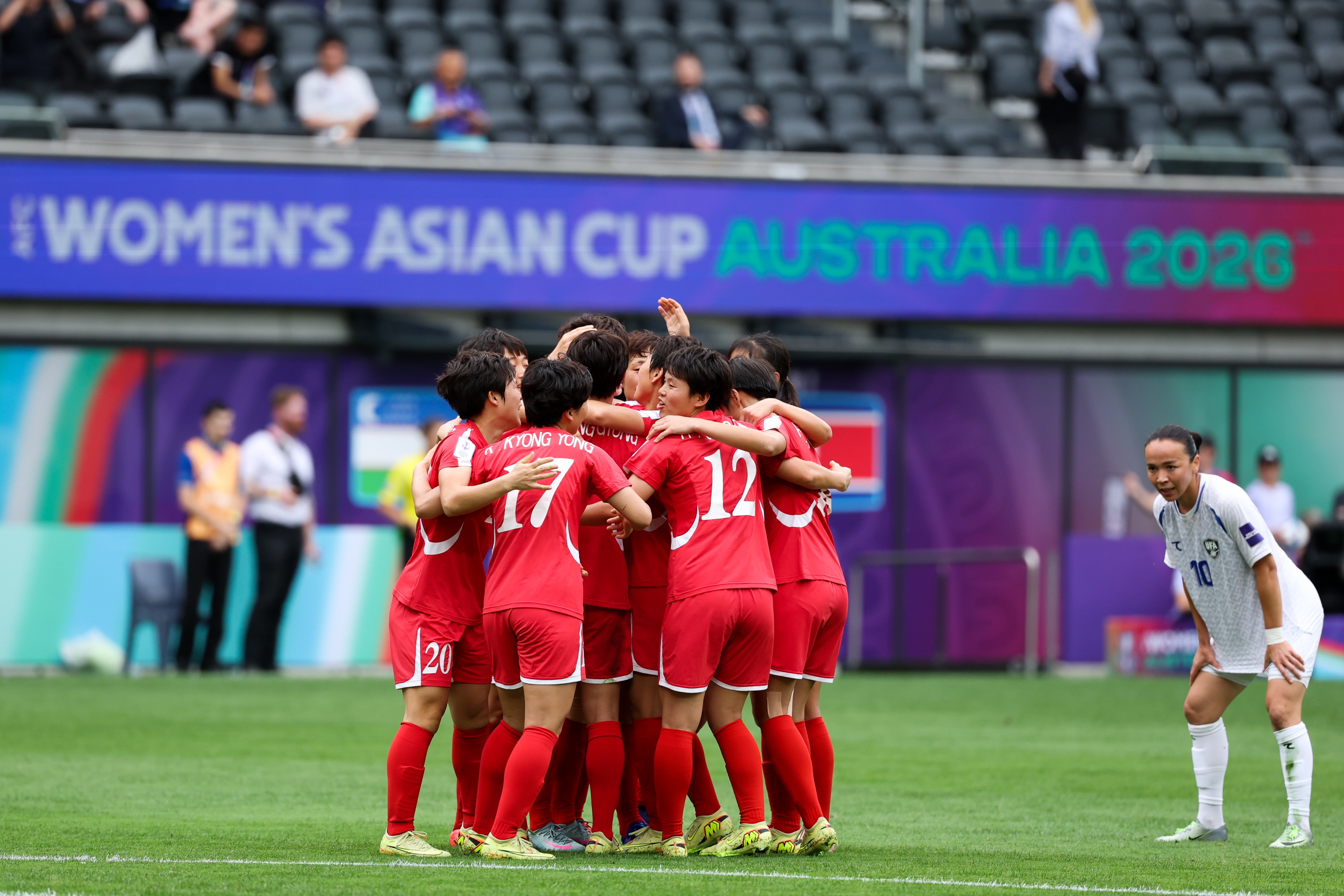 Um grupo de jogadores de futebol em vermelho se reúne depois de marcar um gol