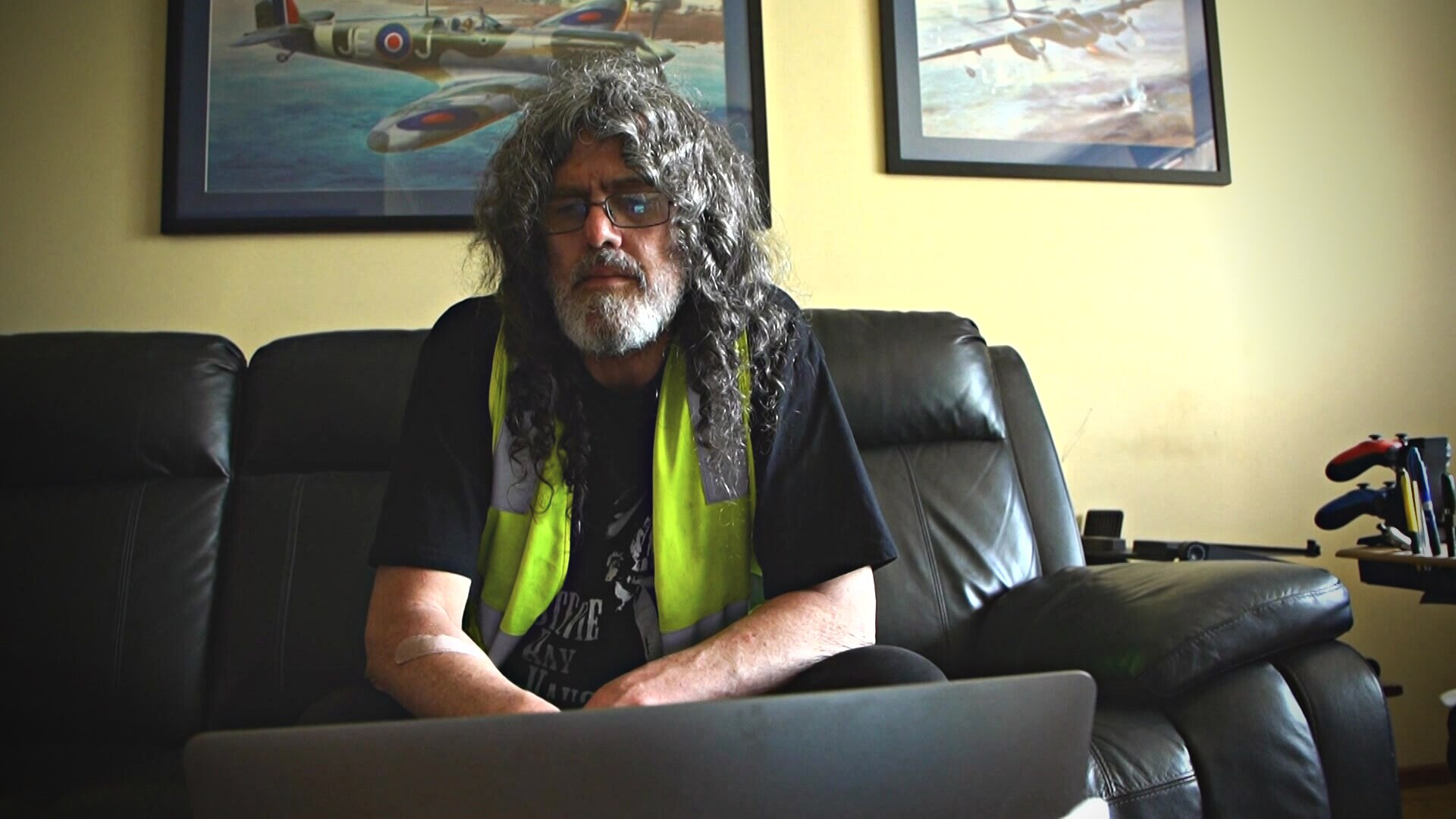 Man sitting on a couch looking at a laptop.