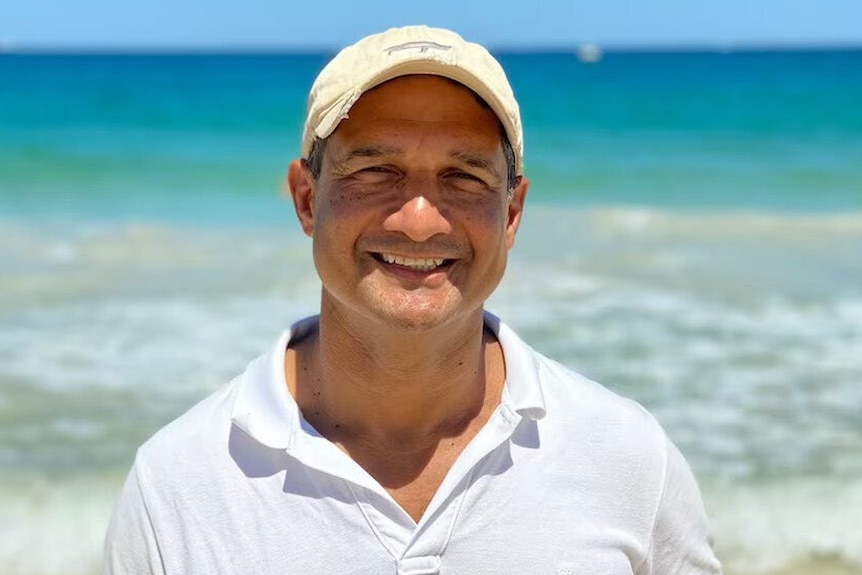 Raymond da Silva Rosa in a white shirt and cap at the beach
