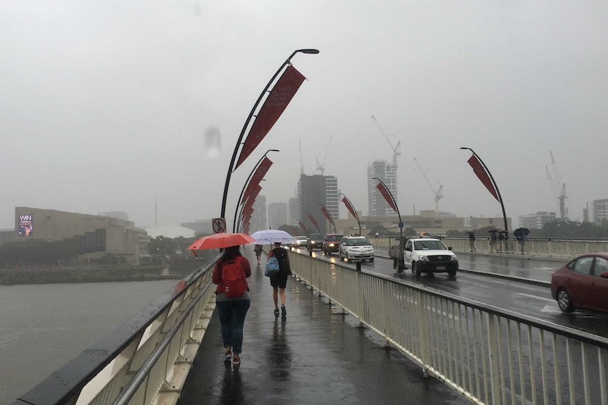 People walk across the bridge to Southbank during the storm that is being dubbed Brisbane's "big wet"