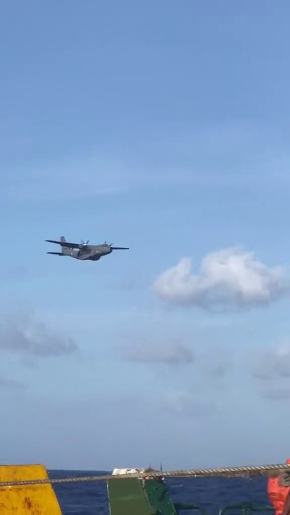 An aircraft flies above a drifting ferry