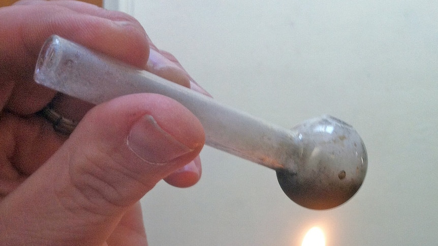 A pipe containing methamphetamine is lit with a lighter.