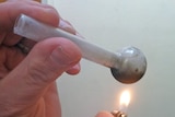 A pipe containing methamphetamine is lit with a lighter.