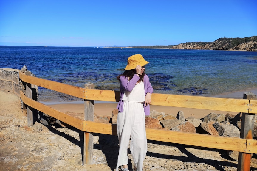 A woman in a bucket hat standing by the sea