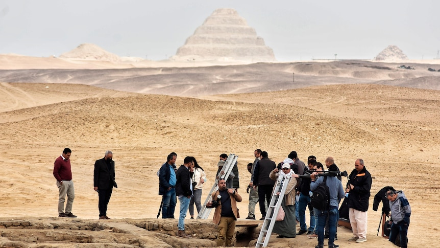 Several people stand around pyramids site