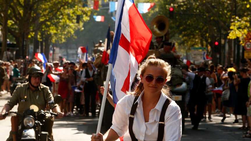 A woman waves a historical flag of WWII during celebrations of the liberation of Paris