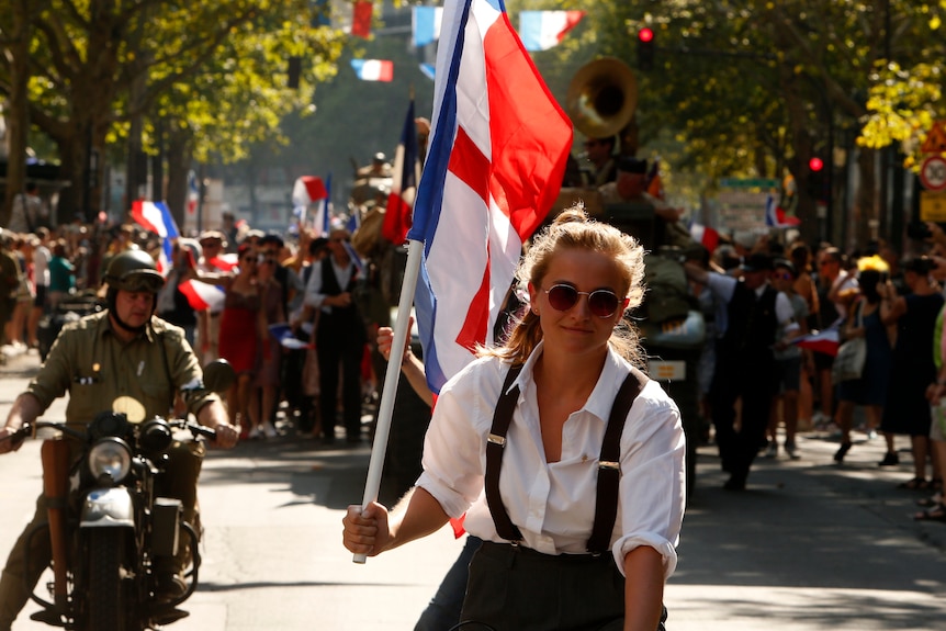 A woman waves a historical flag of WWII during celebrations of the liberation of Paris