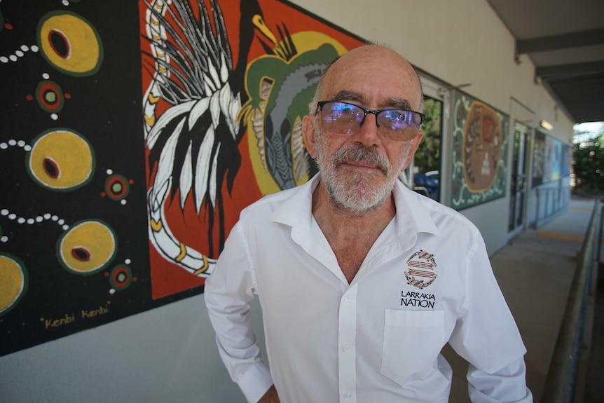 Larrakia Nation CEO Robert Cooper wears classes and a branded shirt. He looks serious.