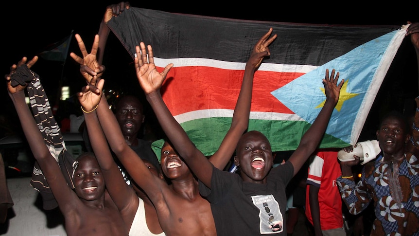 Boys raise their arms in celebration as they parade the South Sudanese flag.