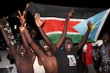 Boys raise their arms in celebration as they parade the South Sudanese flag.