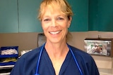 Leah Lokan looks at camera smiling dressed in blue surgical blue uniform