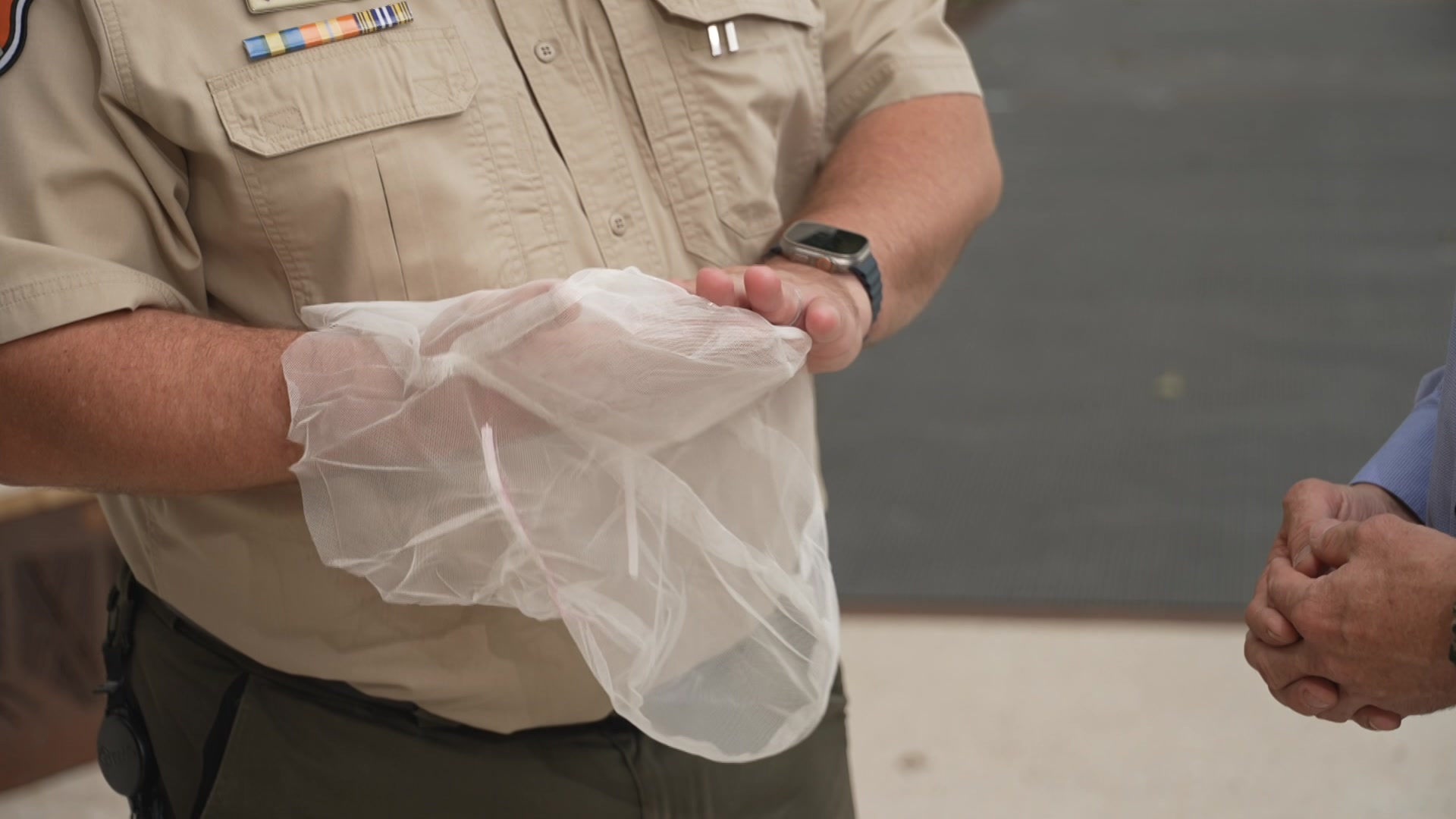 Um homem com uniforme da Correção do NT, segurando um capuz de malha.
