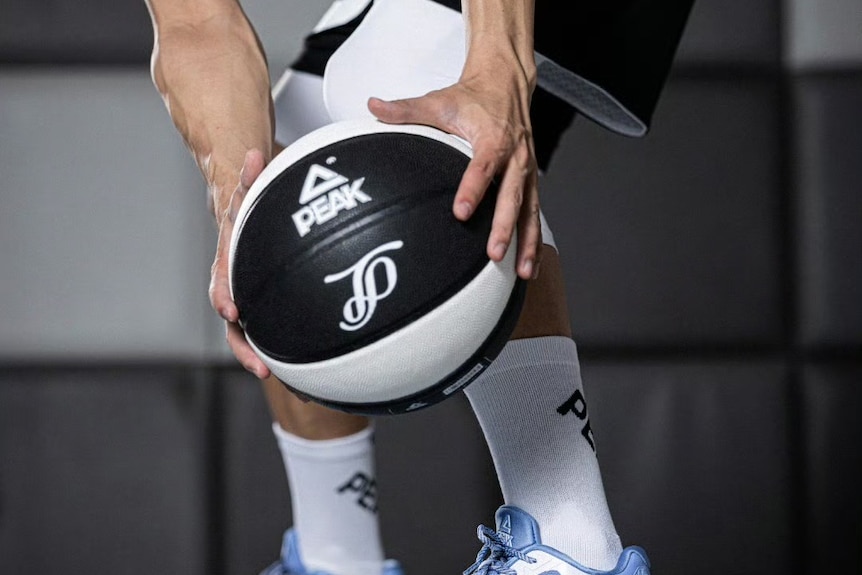 一名男士拿着印有PEAK标识的篮球。