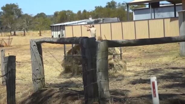 A man on a rural property firing a shotgun.