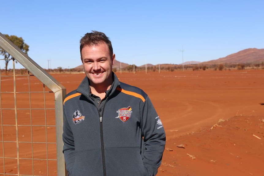 Shawn Ford stands in front of a red dirt oval.