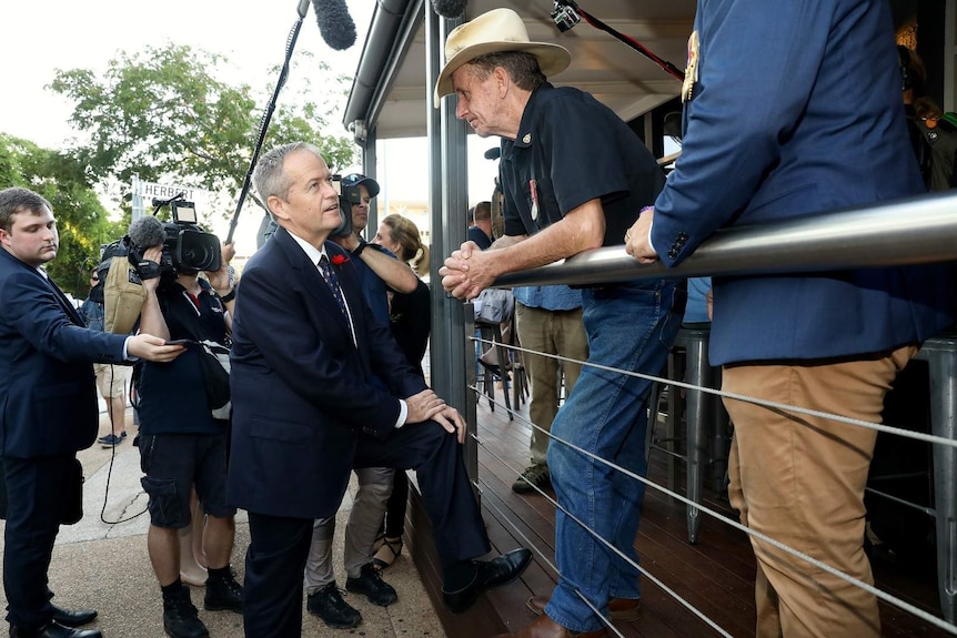 Bill Shorten talks to a man in a hat outside a pub.