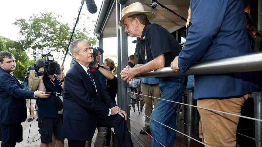 Bill Shorten talks to a man in a hat outside a pub.